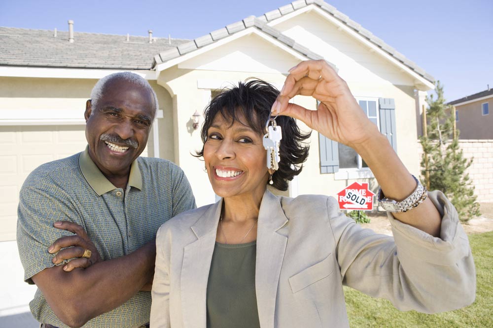 Smiling couple in front of newly purchased home